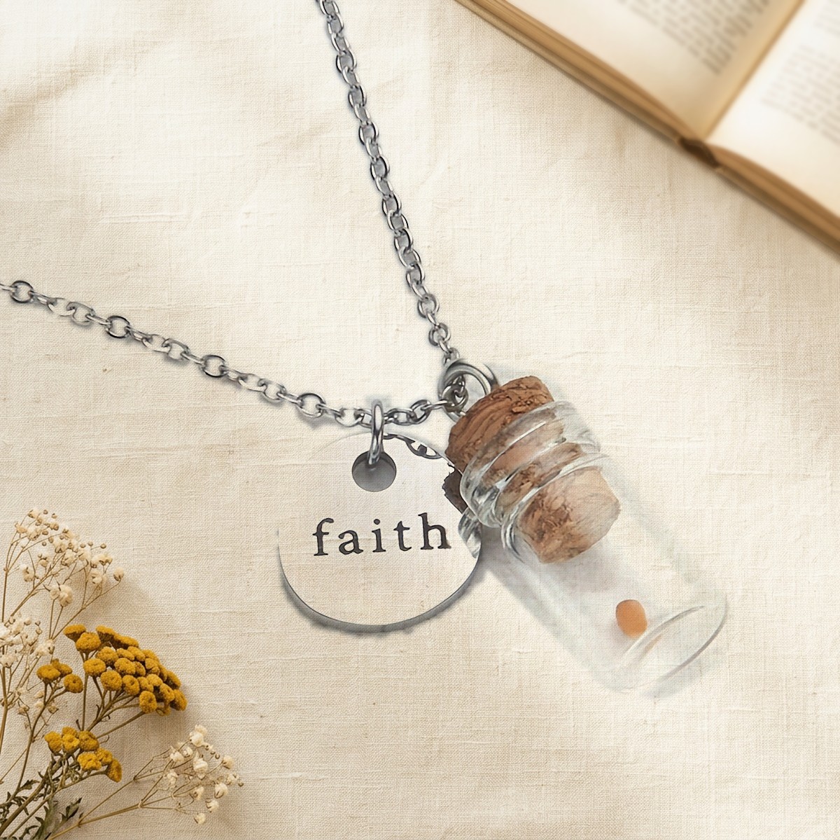 Mustard Seed Faith Necklace: a corked glass vial holding one mustard seed beside a round faith charm, on cream linen